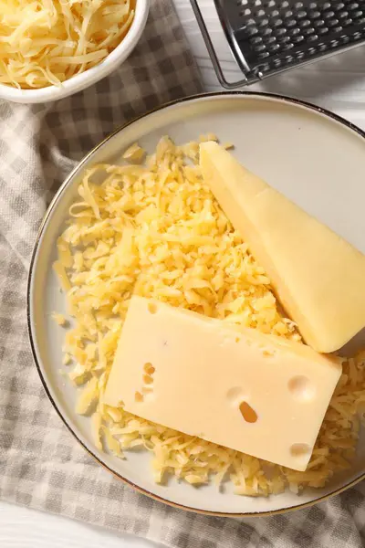 Grated and whole pieces of cheese on table, flat lay