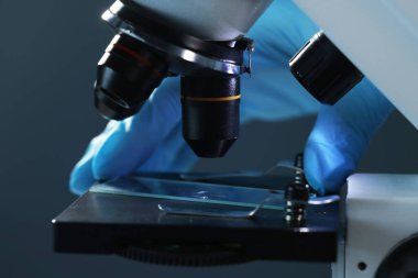 Karanlık arka planda mikroskopla çalışan bilim adamı, yakın plan