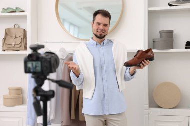 Gülümseyen moda blogcusu evde video kaydederken ayakkabısını gösteriyor