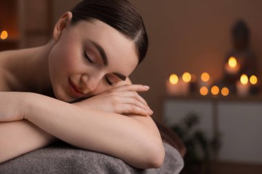 Spa terapisi. Salondaki masaj masasında uzanan güzel genç bir kadın. Mesaj için yer var.