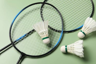 Tüylü badminton mekik horozları ve raketleri yeşil arka planda, görünümün üstünde