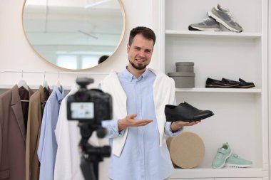 Gülümseyen moda blogcusu evde video kaydederken ayakkabısını gösteriyor