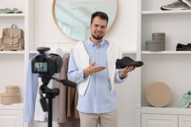 Gülümseyen moda blogcusu evde video kaydederken ayakkabısını gösteriyor