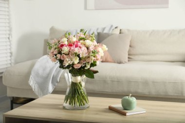 İçerideki ahşap masada vazoda duran bir buket taze çiçek.