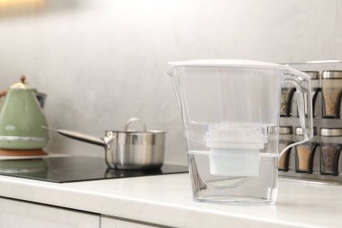 Mutfaktaki beyaz tezgahta su filtresi sürahisi var.