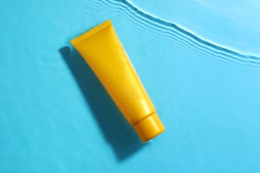 Açık mavi zemin üzerinde suda nemlendirici krem bulunan tüp, üst görünüm.