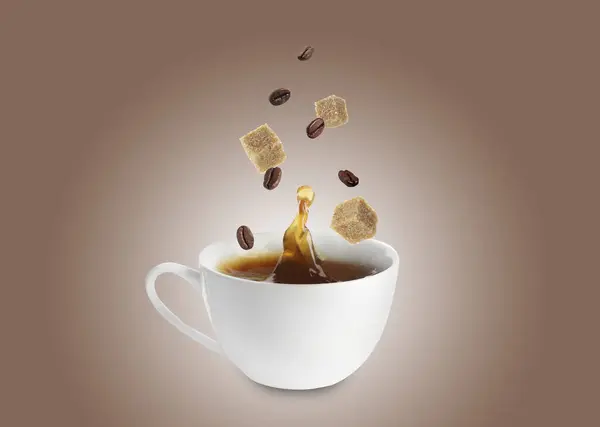 Coffee splashing in cup due to falling roasted beans and sugar cubes on dark beige background