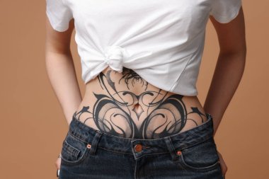 Bej arka planda havalı dövmeleri olan bir kadın, yakın plan.