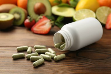 Vitamin hapları, şişe ve ahşap masada taze meyve.