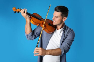 Açık mavi arka planda keman çalan mutlu adam