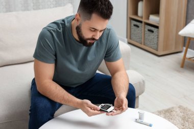 Diyabet testi. Evde glukometresi olan adam