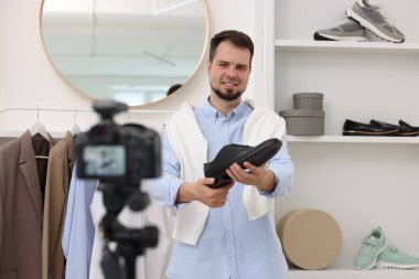 Gülümseyen moda blogcusu evde video kaydederken ayakkabısını gösteriyor