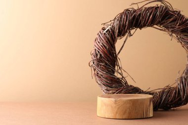 Ürün sunumu. Tahta kürsü ve bej arka planda söğüt dalı çelengi. Metin için boşluk