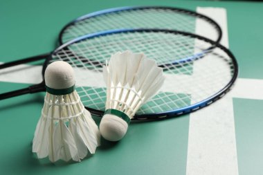 Tüylü badminton mekikleri ve raketleri yeşil masada yakın plan
