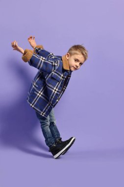 Moda konsepti. Mor arka planda poz veren şık çocuk