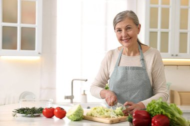 Mutlu ev hanımı mutfakta lahana kesiyor, mesaj için yer var.