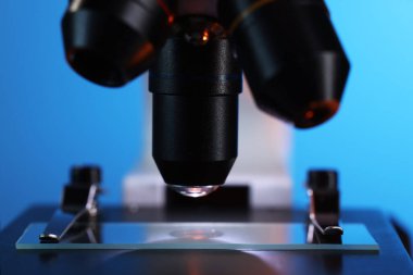 Mavi arkaplanda cam kaydıraklı mikroskop, yakın plan