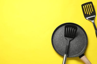 Sarı arka planda spatula ve kızartma tavası düz yerde. Metin için boşluk