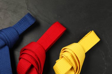 Gri arka planda renkli karate kemerleri, düz yatış