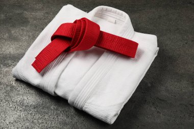 Kırmızı karate kuşağı ve gri dokulu arka planda beyaz kimono.