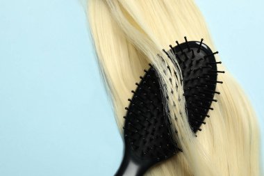 Açık mavi arka planda sarı saç telli şık fırça, üst manzara. Metin için boşluk