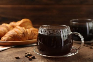 Cam bardakta sıcak kahve ve ahşap masada fasulye, yakın plan.