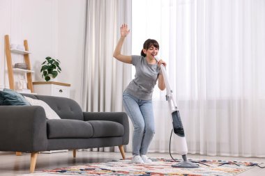 Mutlu genç ev hanımı evde temizlik yaparken eğleniyor.