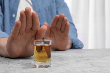 Alkol bağımlılığı. Gri desenli masada viski içmeyi reddeden adam, yakın plan.