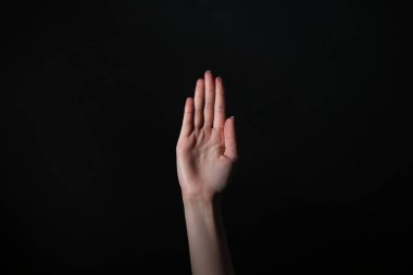 Siyah arka planda açık avuç gösteren kadın, yakın plan