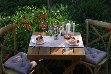 Baharda çiçekli vazo, şarap ve pasta bahçede romantik bir randevuya servis edilir.