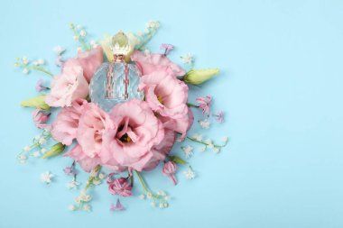 Parfüm ve çiçek dekoru açık mavi arka planda, düz yerde. Metin için boşluk