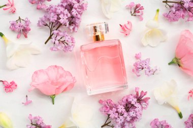 Parfüm ve çiçek dekoru beyaz arka planda, düz yerde.