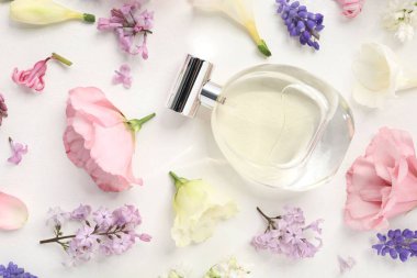 Parfüm ve çiçek dekoru beyaz arka planda, düz yerde.