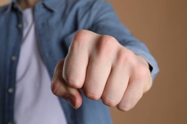 Bej arka planda dövmesi için yer olan yumruğunu gösteren adam, seçici odak