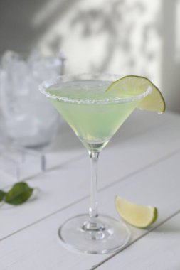 Lezzetli Margarita kokteyli beyaz ahşap masada limon ve cam.
