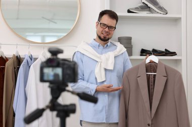 Gülümseyen moda blogcusu evde video kaydederken kıyafetlerini gösteriyor