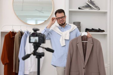 Gülümseyen moda blogcusu evde video kaydederken kıyafetlerini gösteriyor