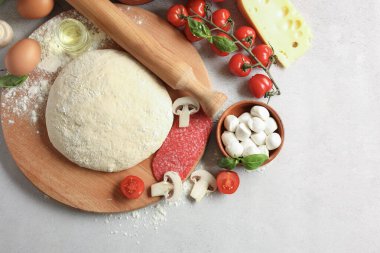 Pizza hamuru, ürünler ve gri desenli masa üzerindeki merdane düz.