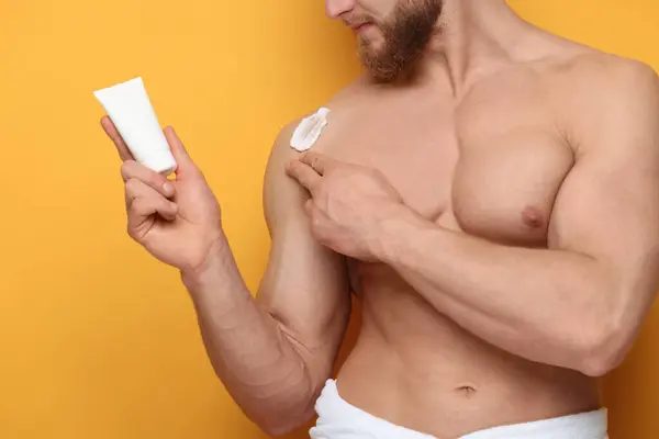 Man Applying Moisturizing Cream His Shoulder Orange Background Closeup Imagem De Stock