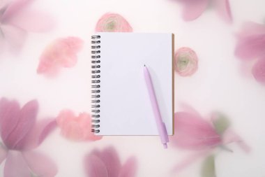 Konuk listesi. Bahar çiçekli arka planda defter ve kalem, üst görünüm