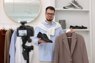 Gülümseyen moda blogcusu evde video kaydederken kıyafetlerini gösteriyor