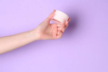 Violet 'in arka planında elinde krema kavanozu olan bir kadın, yakın plan. Metin için boşluk