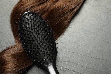 Kahverengi saç telli, koyu gri masadaki şık fırça, üst manzara. Metin için boşluk