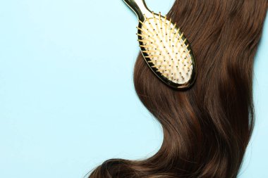 Açık mavi zemin üzerinde kahverengi saç teli olan şık fırça, üst manzara. Metin için boşluk