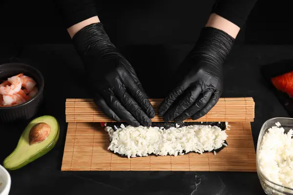 Chef Handskar Inslagning Sushi Rulle Vid Mörkt Strukturerat Bord Närbild — Stockfoto