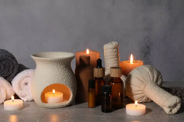 Aromatherapy. Scented candles and spa products on gray textured table