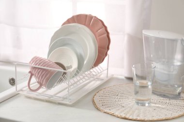 Farklı temiz bulaşık takımları, bardak, cam ve filtre sürahi içerideki aydınlatma masasında.