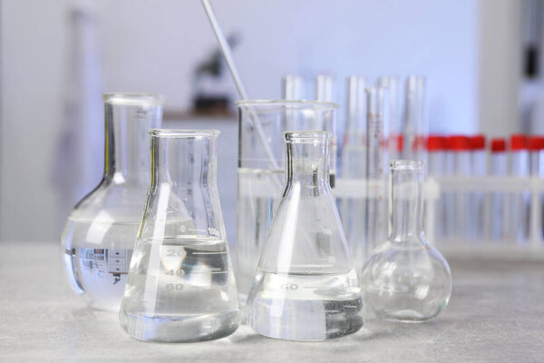 лабораторный анализ. Различные изделия из стекла на светло-сером столе в помещении