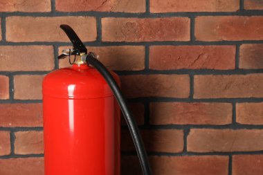 Tuğla duvarın yanında kırmızı bir yangın söndürücü, metin için yer var.