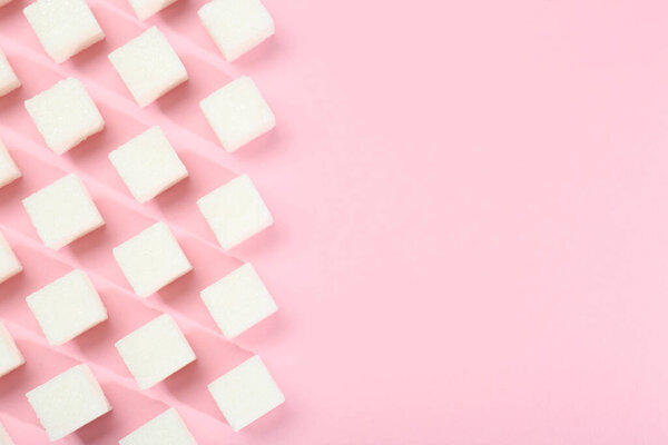 White sugar cubes on pink background, top view. Space for text